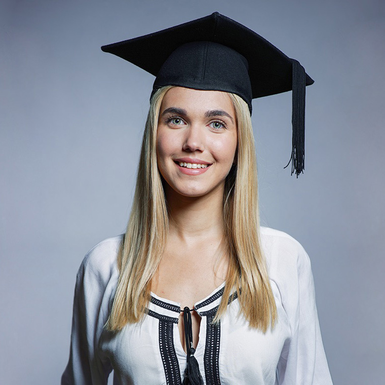 Mia Mijović duge, plave kose, sa graduation hat-om na glavi pozira za fotografa.